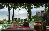 a man and woman sitting on a couch in front of the ocean at Anantara Rasananda Koh Phangan Villas in Thong Nai Pan Noi