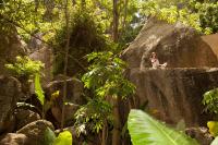 a woman sitting on a large rock in a forest at Anantara Rasananda Koh Phangan Villas in Thong Nai Pan Noi