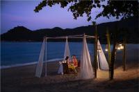 two people sitting at a table on the beach at night at Anantara Rasananda Koh Phangan Villas in Thong Nai Pan Noi