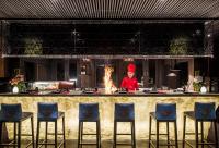 a chef standing behind a kitchen counter with a fire at Anantara Rasananda Koh Phangan Villas in Thong Nai Pan Noi