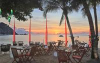 a restaurant on the beach at sunset with palm trees at Anantara Rasananda Koh Phangan Villas in Thong Nai Pan Noi