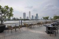 a row of tables and chairs next to a body of water at Chatrium Hotel Riverside Bangkok in Bangkok