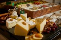 a table topped with different types of cheeses and fruit at Hotel Metropol by Maier Privathotels in Munich