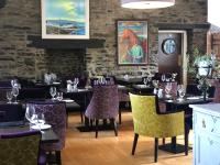 un restaurante con mesas y sillas con sillas moradas en Port Charlotte Hotel, en Port Charlotte