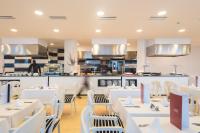 Un restaurante con mesas y sillas blancas y una cocina. en Cala Millor Garden Hotel - Adults Only, en Cala Millor