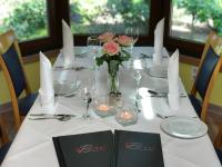 Una mesa con un mantel blanco y un jarrón de flores. en Gasthaus Beinker, en Ostercappeln