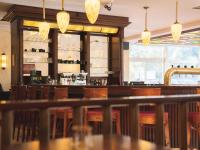 Un bar en un restaurante con sillas de madera y luces. en Hotel Löwenstein, en Gerolstein