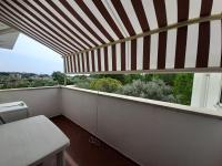 a balcony with a striped roof with a table and a window at a due passi dal mare in Diamante