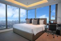 Un dormitorio con una cama, un escritorio y ventanas. en The Alpha Suites, en Manila
