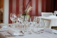 a table with wine glasses and a vase with flowers at Toftaholm Herrgård in Lagan