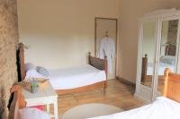 a bedroom with two beds and a table and a mirror at La Merise Gite in Villefranche-dʼAlbigeois