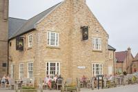 The Bay Filey Holiday Village في Filey: مبنى كبير من الطوب يجلس الناس أمامه على طاولات