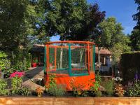 an orange and green bird cage in a garden at Mobil home PREMIUM 35m2 3 chambres 6 personnes in Arès