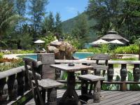 a wooden deck with a table and chairs next to a pool at Malibu Beach Bungalows in Chaloklum