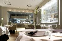 a restaurant with white tables and chairs and a counter at Hotel Repubblica 55 in Biella