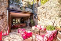 a patio with pink chairs and tables and a stone wall at Chambre et Gite Le Roc sur l&#39;Orbieu in Carcassone