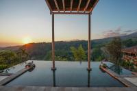 a view of a pool with the sunset in the background at Rinjani Lodge in Senaru