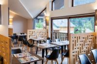 een restaurant met tafels en stoelen en grote ramen bij SOWELL Family Valfrejus in Valfréjus