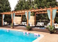 a pool with a pergola and chairs next to a swimming pool at Hotel Preston Nashville Airport in Nashville
