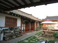 eine Terrasse eines Hauses mit einem Tisch und einem Sonnenschirm in der Unterkunft Hanok Raon in Gyeongju