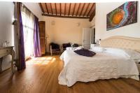 Un dormitorio con una gran cama blanca y suelos de madera. en L&#39;Albero Di Gamelì, en Chiusi