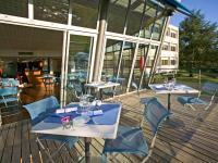 2 mesas y sillas en una terraza con un edificio en Mercure Lyon Charbonnières, en Charbonnières-les-Bains