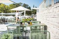 ザダルにあるFalkensteiner Premium Mobile Homes and Camping Zadarのテーブルと椅子のあるパティオを歩いている人