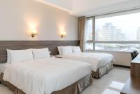 two beds in a hotel room with a large window at Hotel Leisure Beitou in Taipei