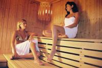 two women sitting on a bench in a sauna at T2 RESIDENCE 3 ETOILES Piscine chauffée Sauna Hammam in Cauterets