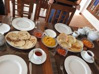 a table with plates of food and cups of tea at Nilowin Glenanore Guesthouse in Haputale