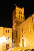 a large stone building with a clock tower at night at Maison au pied de la cathédrale in Elne
