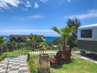 a rv parked next to chairs and the ocean at Tudor Dynasty Homestay in Yanliau