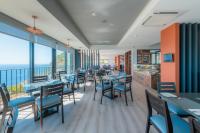 ein Restaurant mit Tischen und Stühlen und Blick auf das Meer in der Unterkunft Engenho Velho Hotel & Restaurante - Adults Only in Arco da Calheta