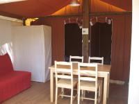 a dining room with a table and chairs and a red couch at Camping Mille Étoiles in Labastide-de-Virac