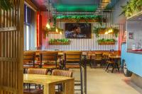 a restaurant with wooden tables and chairs and plants at Kick Ass Greyfriars (18+) in Edinburgh