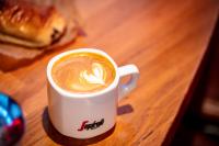 a cup of coffee sitting on a wooden table at Kick Ass Greyfriars (18+) in Edinburgh