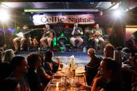 a group of people sitting at a table in a bar with musicians at Arlington Hotel O'Connell Bridge in Dublin