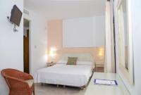 a bedroom with a white bed and a chair at Hostal Doña Lola Marina in Zahara de los Atunes