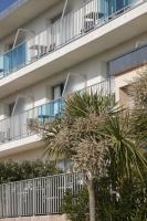 an apartment building with palm trees in front of it at Hotel Europa in Quiberon