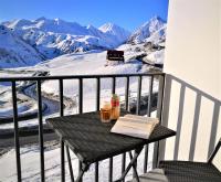 una mesa con un libro y bebidas en un balcón con montañas cubiertas de nieve en Panorama Vista Gudauri Apartments, en Gudauri