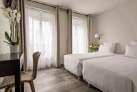 a hotel room with two beds and a desk and a window at Hotel Beauvoir in Paris