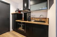 a kitchen with black cabinets and a sink at Appartement Croisé Laroche 40m2 in Marcq-en-Baroeul