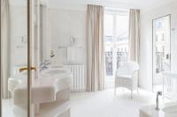 a white bathroom with two sinks and a chair at Le Bristol Paris - an Oetker Collection Hotel in Paris
