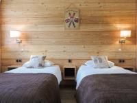 two beds in a room with wooden walls at Logis Le Vernay in Autrans