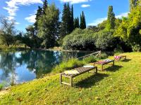 two benches sitting on the grass near a lake at Le Mas de Patrice in Quissac