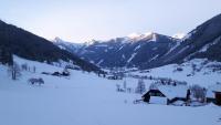 a house in the snow with mountains in the background at Der Perweinhof in Donnersbachwald