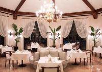 un ristorante con tavoli e sedie bianchi e un lampadario di Hotel Karia Princess a Bodrum City
