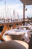 a row of tables and chairs on a dock with boats at Mosella Suite Hotel in Sottomarina