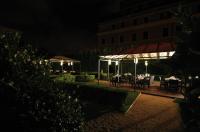 a dining area with tables and umbrellas at night at Villa Spalletti Trivelli - Small Luxury Hotels of the World in Rome