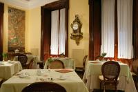 a dining room with tables and a clock on the wall at Villa Spalletti Trivelli - Small Luxury Hotels of the World in Rome
